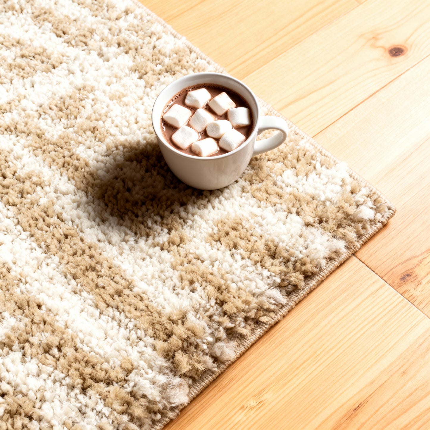White cup of hot chocolate with marshmallows on beige and white shaggy rug on wooden floor