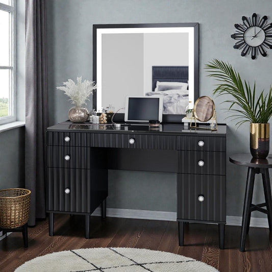 Modern black vanity table with large mirror, decorative plants, makeup accessories, and tablet in stylish bedroom