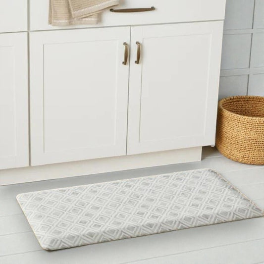 Modern white kitchen cabinets with bronze handles, textured floor mat, and woven basket on tiled floor