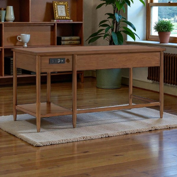 wooden office desk with power outlets on side, placed on beige rug in room with wooden floor and bookshelf