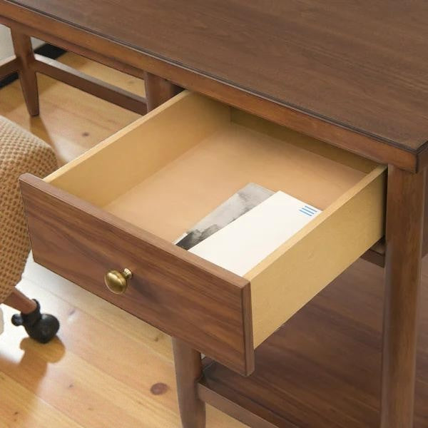 wooden desk with a single open drawer containing papers on a hardwood floor