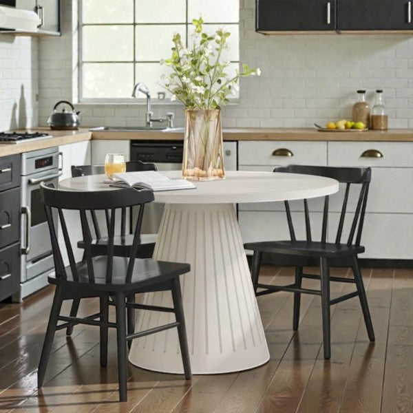 Modern kitchen with white round pedestal dining table, black chairs, and decorative vase with green plants