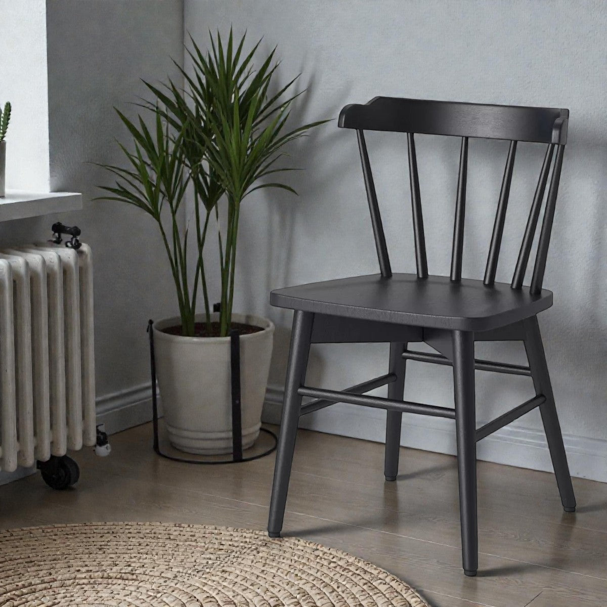 Black wood spindle-back chair next to potted palm plant and radiator in modern interior