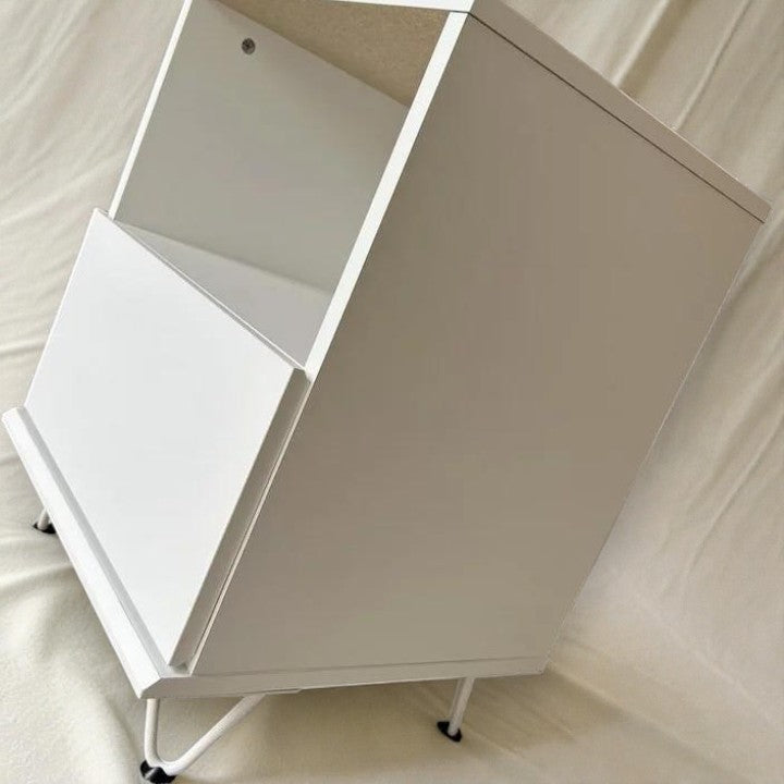 modern white nightstand with open shelf and angled legs on light fabric background