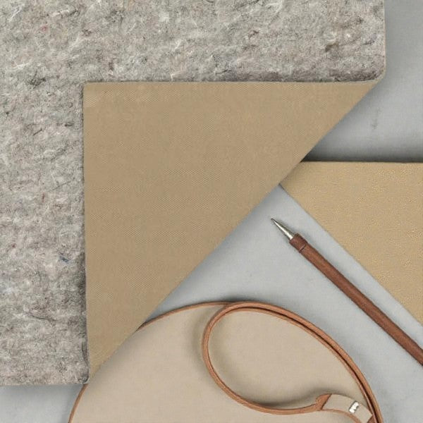 Natural wool fabric with beige backing, leather strap, and wooden pen on a gray surface