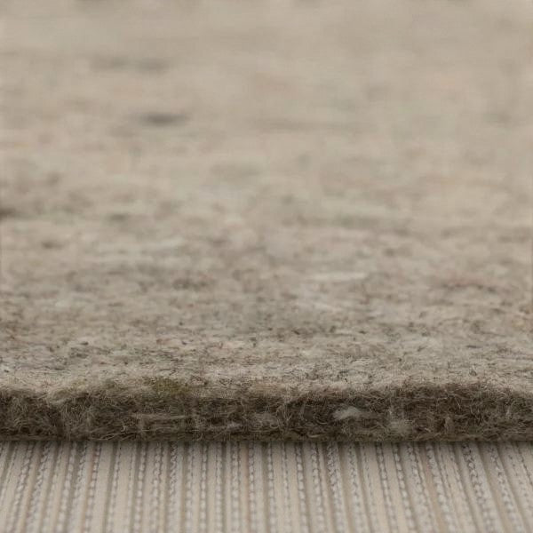 Close-up of a thick, beige wool rug with a textured fabric surface on a striped woven floor covering