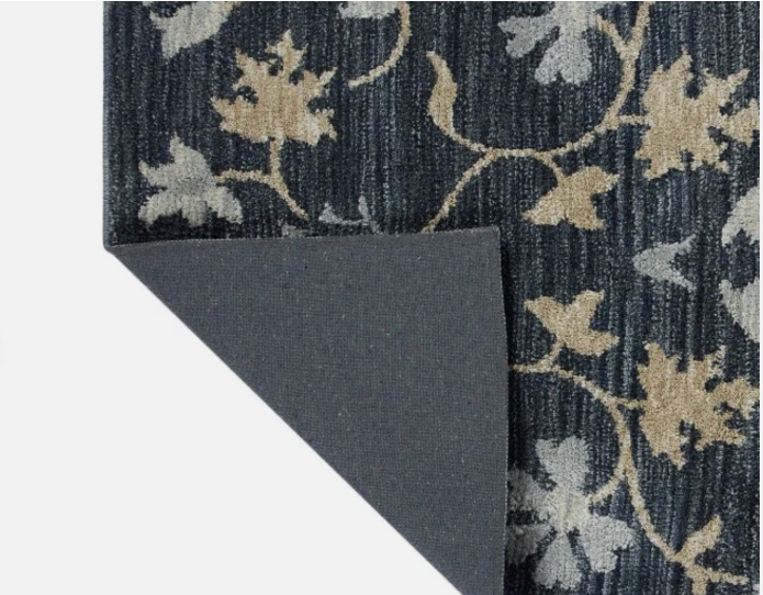 Dark blue floral patterned area rug with beige and light gray leaves, showing folded corner